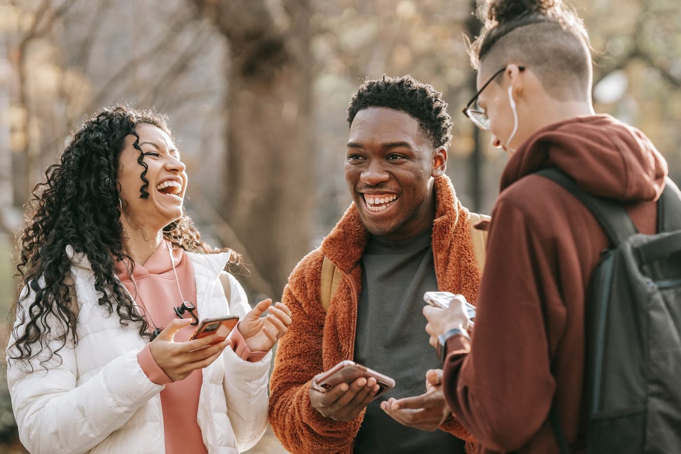 Three friends laughing together while looking at their phones